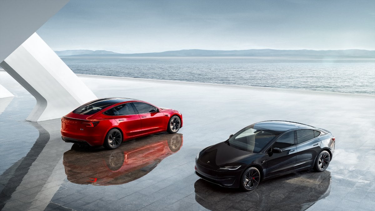 Red and black 2025 Tesla Model 3 Performance sedans parked on reflective surface with misty ocean horizon