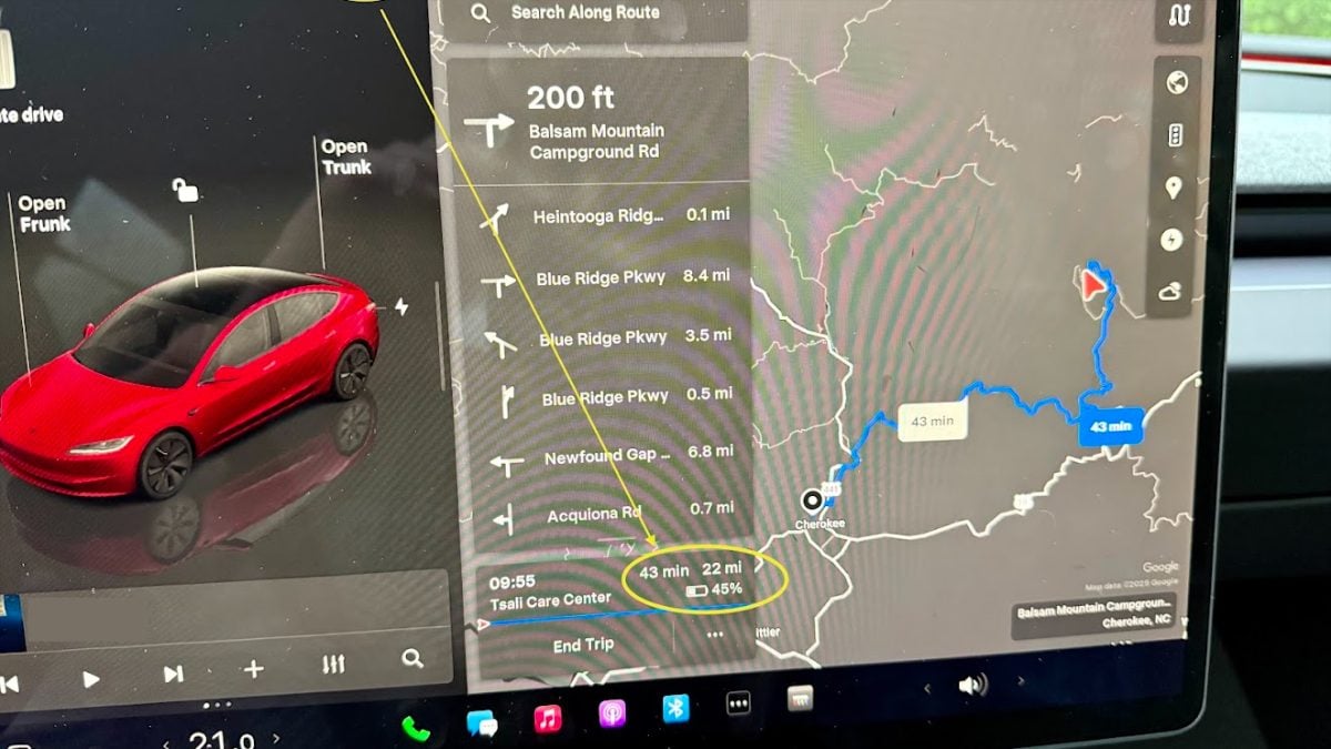 A car backseat with the door open, displaying a green sleeping pad, a white pillow, a red bag, a black container, and some other gear.