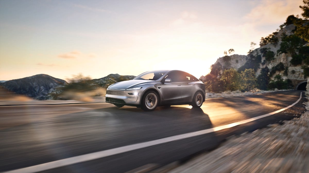 Silver 2025 Tesla Model Y Juniper driving on winding mountain road at sunset, blurred motion showing speed and dynamic movement