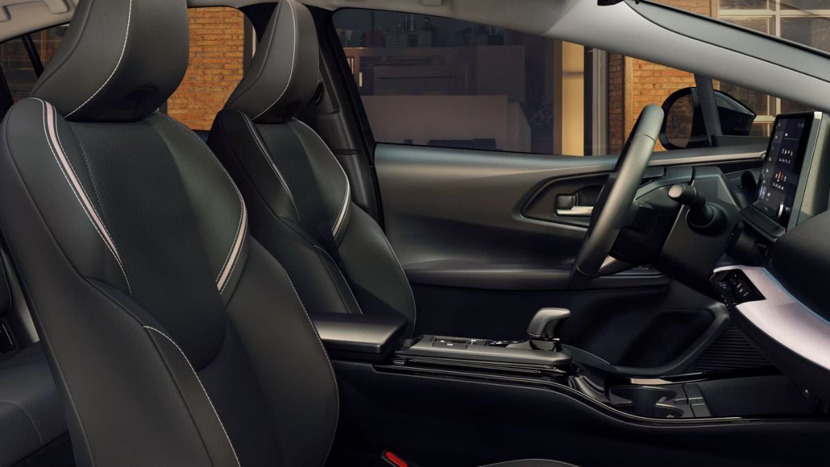 2025 Toyota Prius interior featuring premium black leather seats with contrast stitching, modern dashboard with digital displays, viewed from passenger side.
