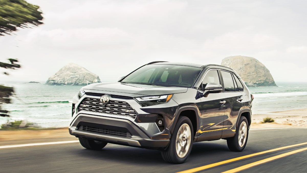 A 2025 Toyota RAV4 compact SUV shown from the front three-quarter angle in a studio setting, displaying its modern grille and LED headlights.