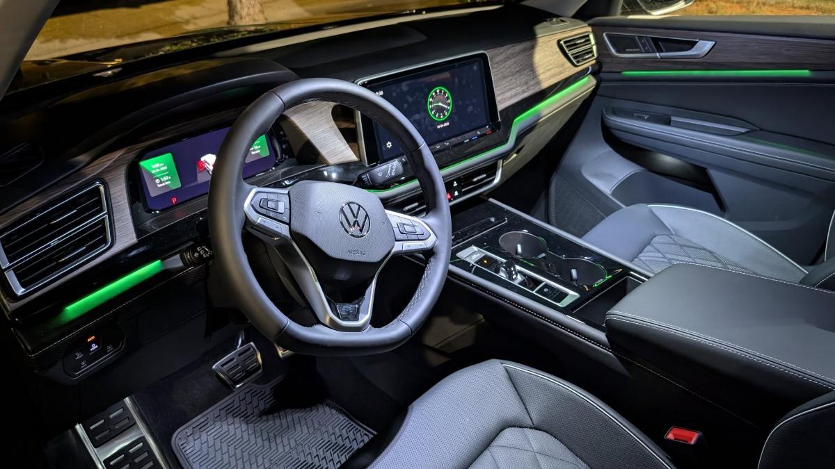 Car interior with a steering wheel, digital dashboard, and illuminated green accents.