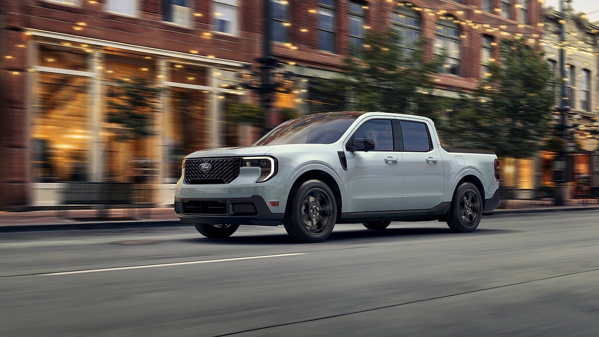 Space White 2025 Ford Maverick Lariat with Black Appearance Package driving through a city street.