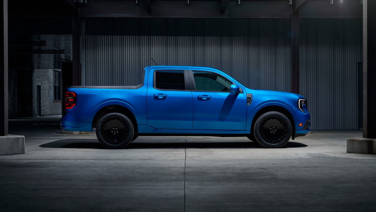 Blue 2025 Ford Maverick Lobo shown in side profile inside a dark industrial setting.