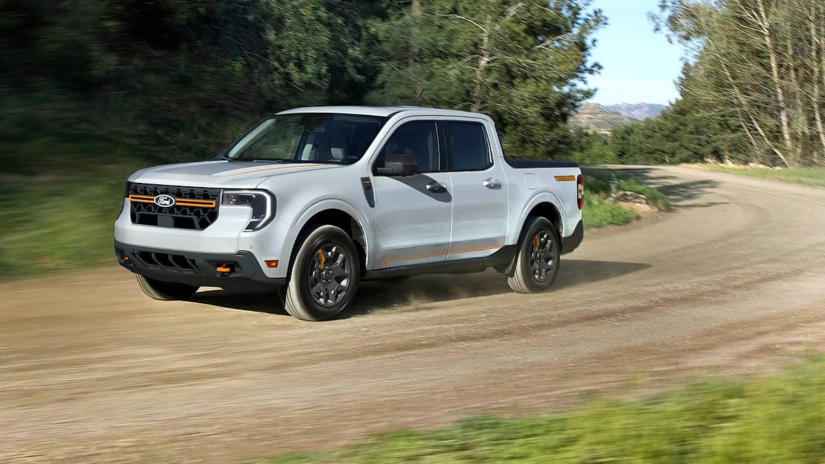 White 2025 Ford Maverick Tremor driving on a dirt road in a front three-quarter action view.