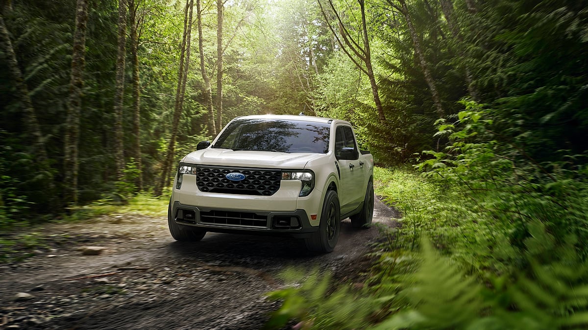Desert Sand 2025 Ford Maverick XLT FX4 driving on a forest trail in a front three-quarter view.