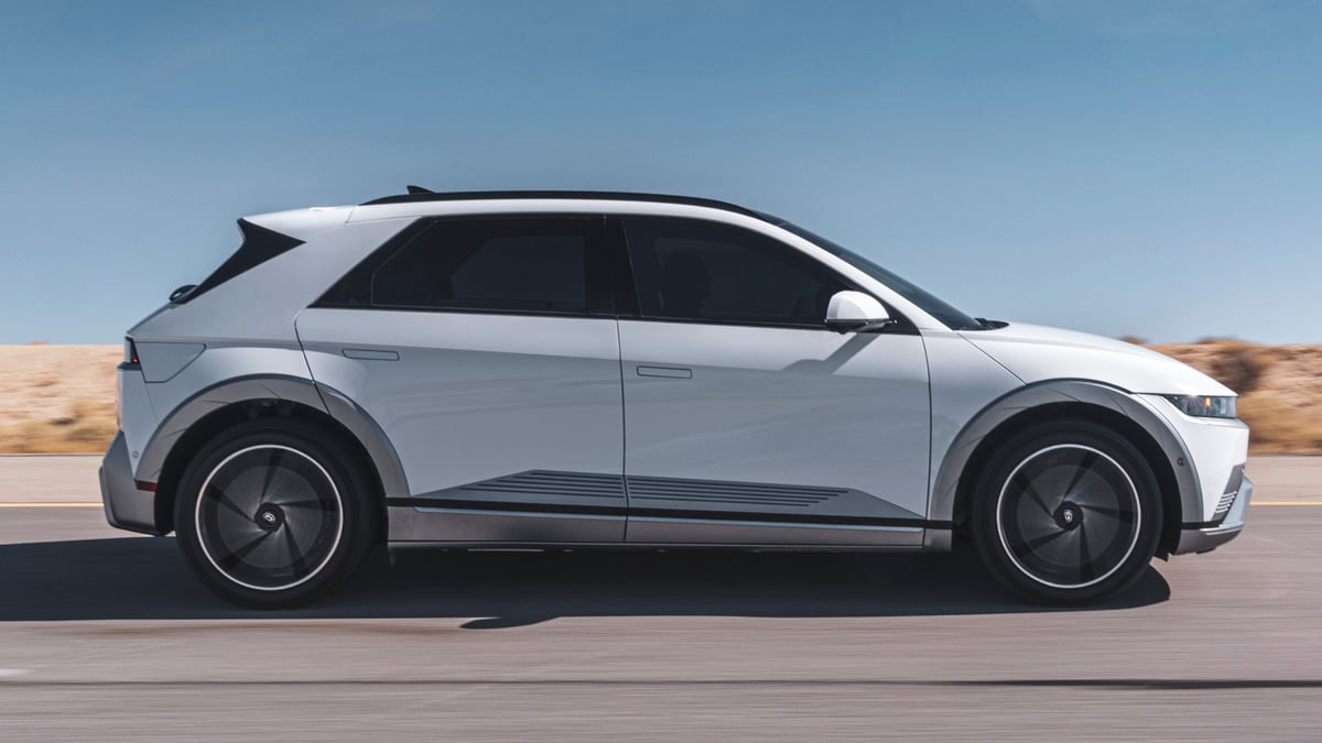 White 2025 Hyundai Ioniq 5 Limited driving through a desert landscape in a full side-profile view.
