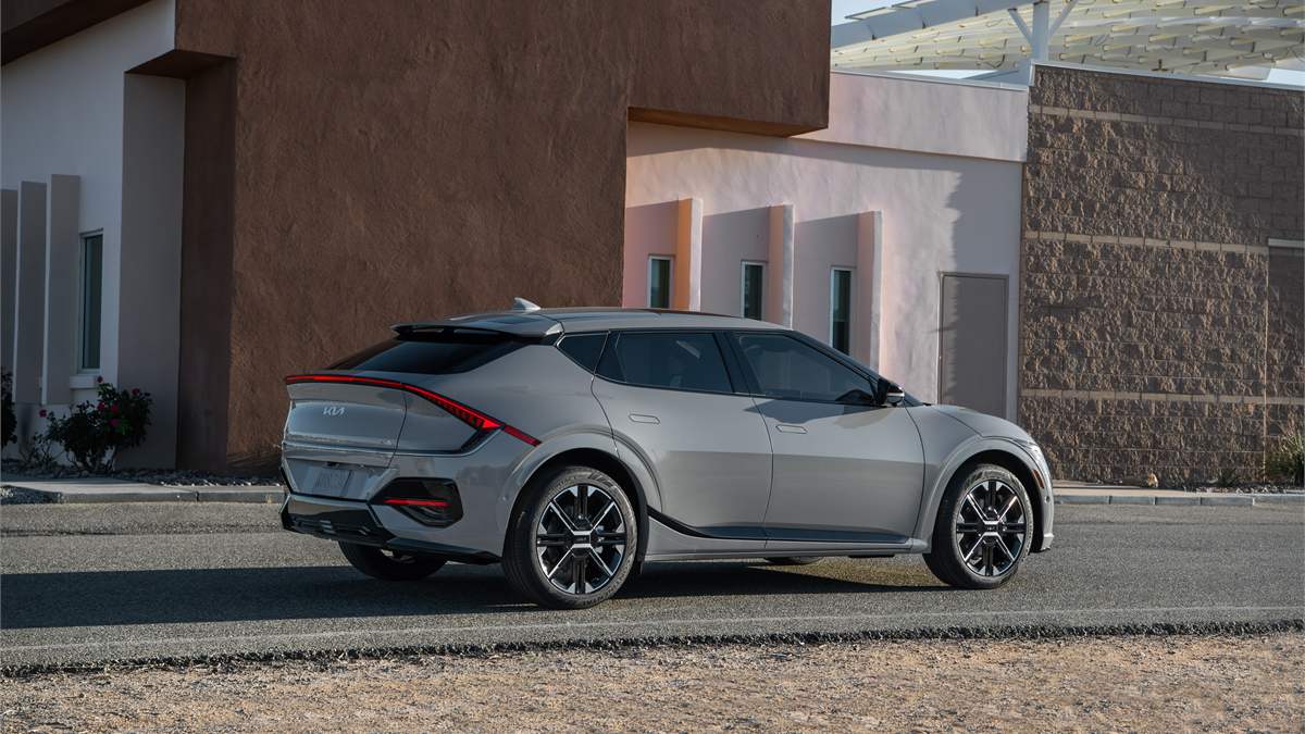 Rear three-quarter view of a gray Kia EV6 electric vehicle, featuring sculpted body lines, LED taillights, and sporty crossover stance.