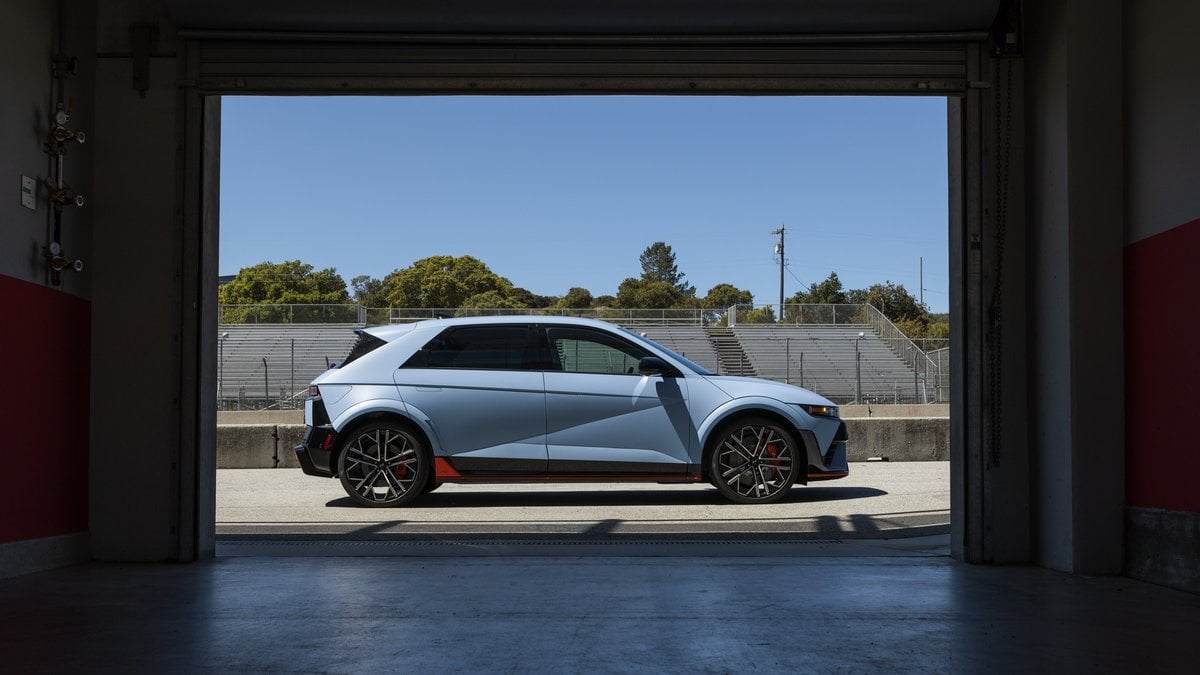 2025 Hyundai IONIQ 5 N in Performance Blue Matte viewed through garage door, side profile with racetrack grandstands visible