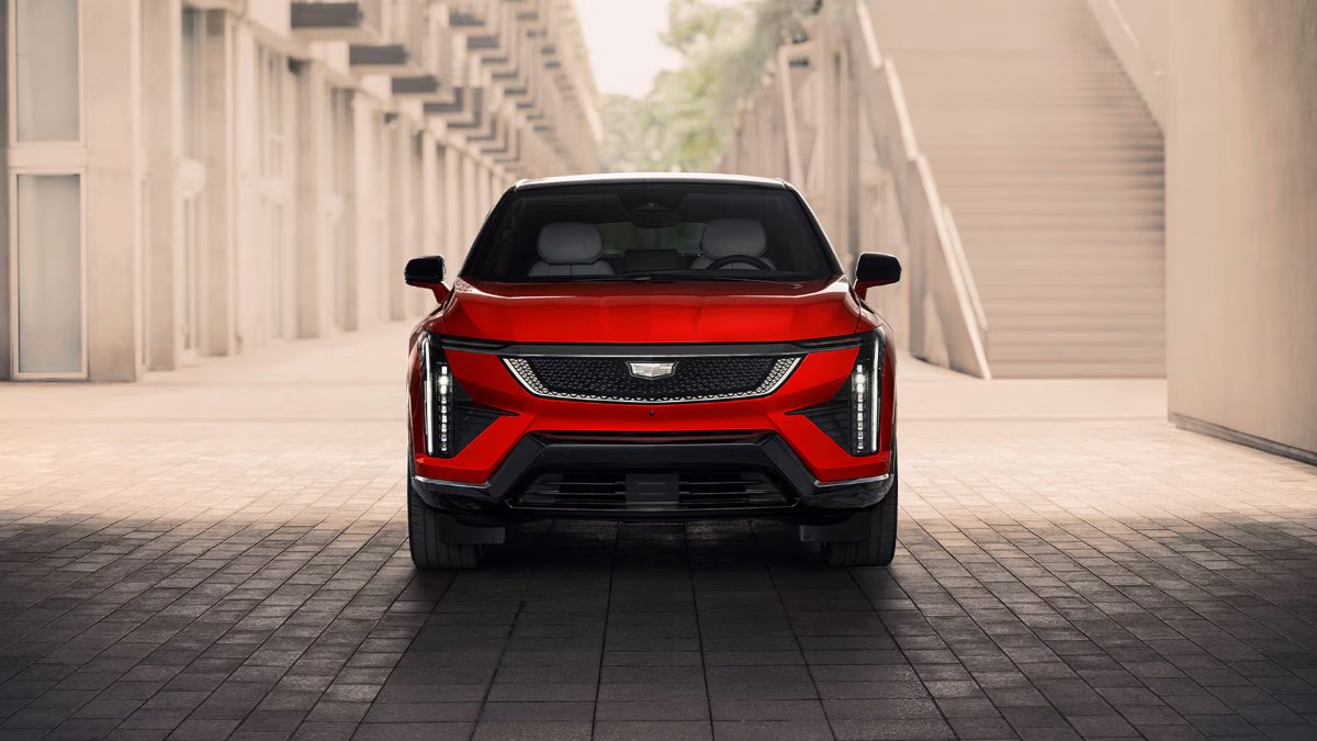 Red SUV parked in a modern architectural setting with stairs and geometric buildings.