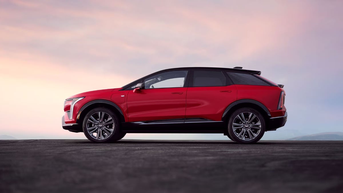 Red SUV parked on asphalt with a pink and blue sky in the background.