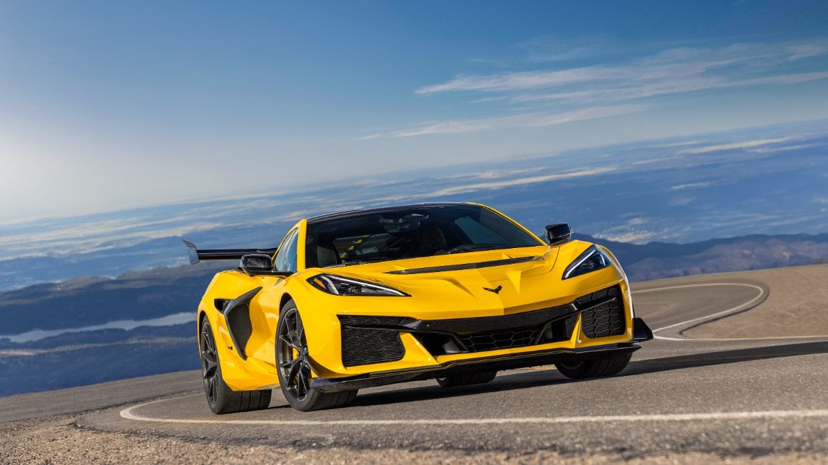 2023 Chevrolet Corvette Z06 in Accelerate Yellow, photographed at three-quarter front angle on mountain road with dramatic sky backdrop.