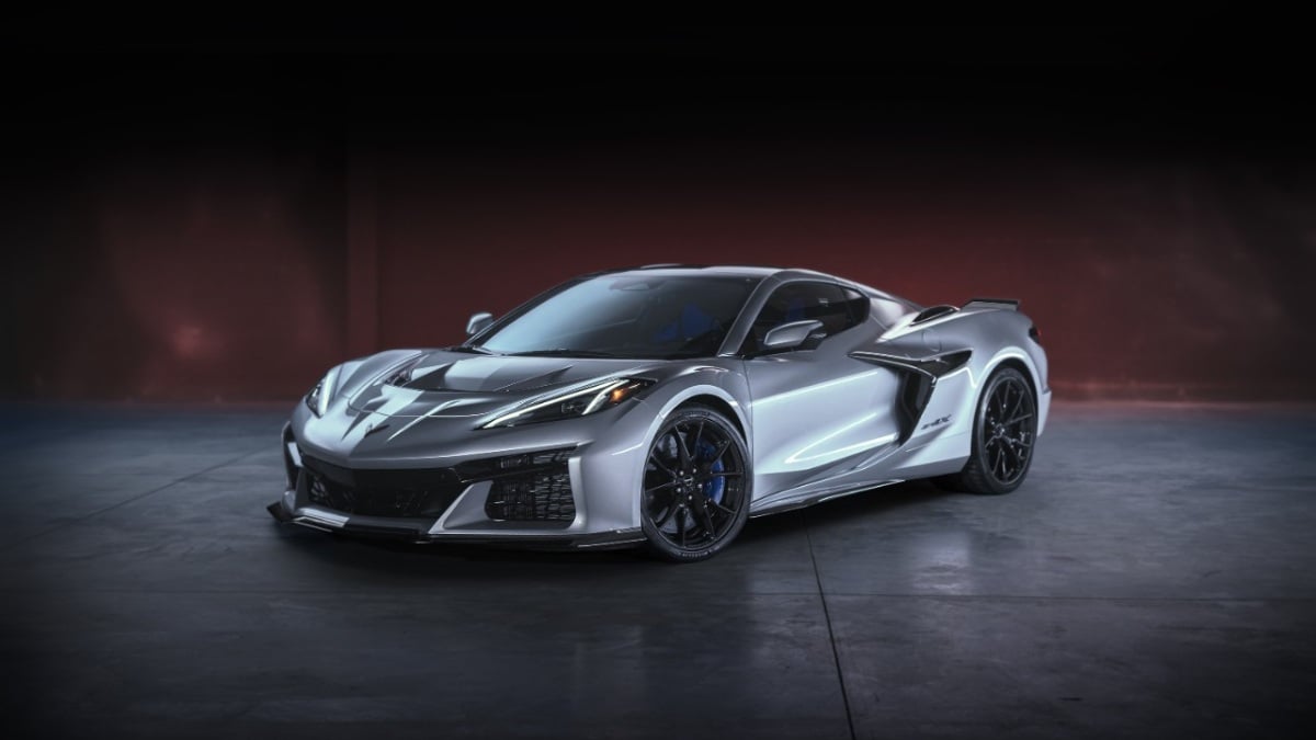2026 Chevrolet Corvette ZR1X in silver, front three-quarter view, featuring aggressive aerodynamics, black wheels, and blue brake calipers, photographed in dark studio setting.