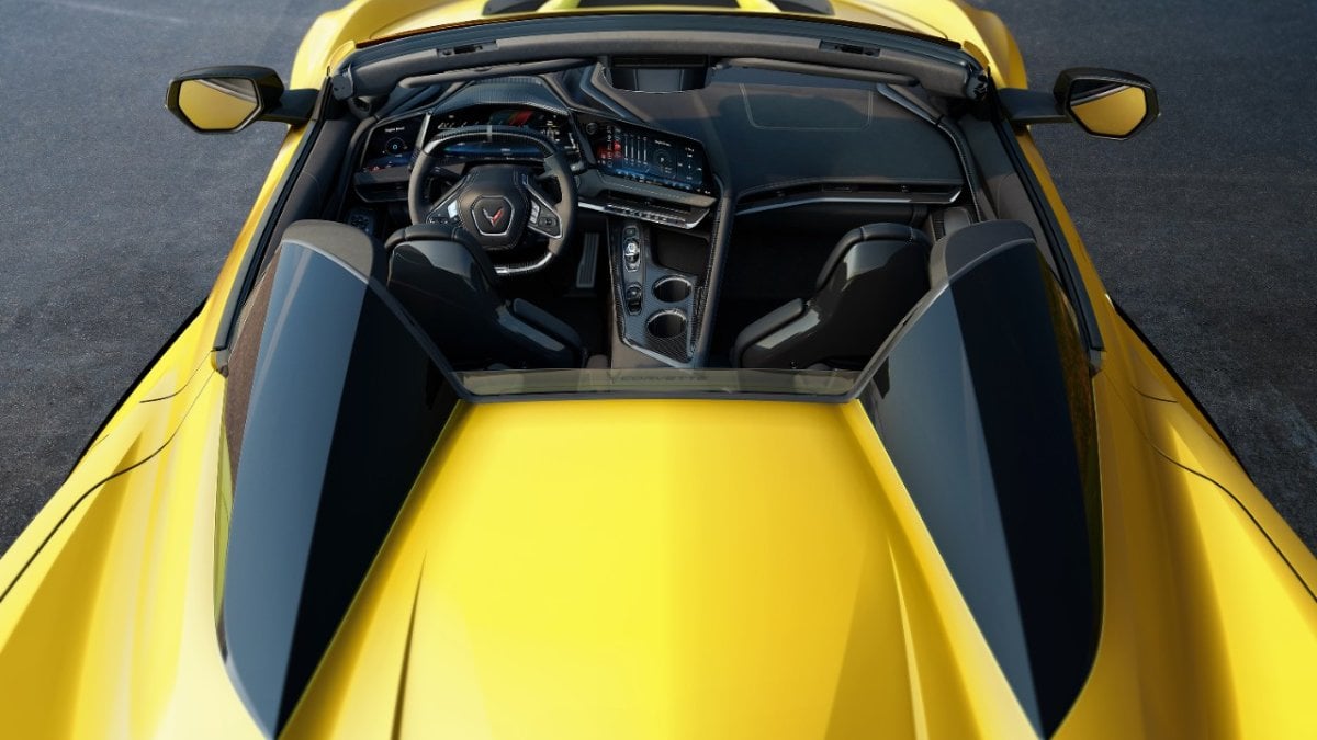 2026 Chevrolet Corvette C8 interior view showing black leather cockpit, digital dashboard, and yellow exterior hood visible through windshield.