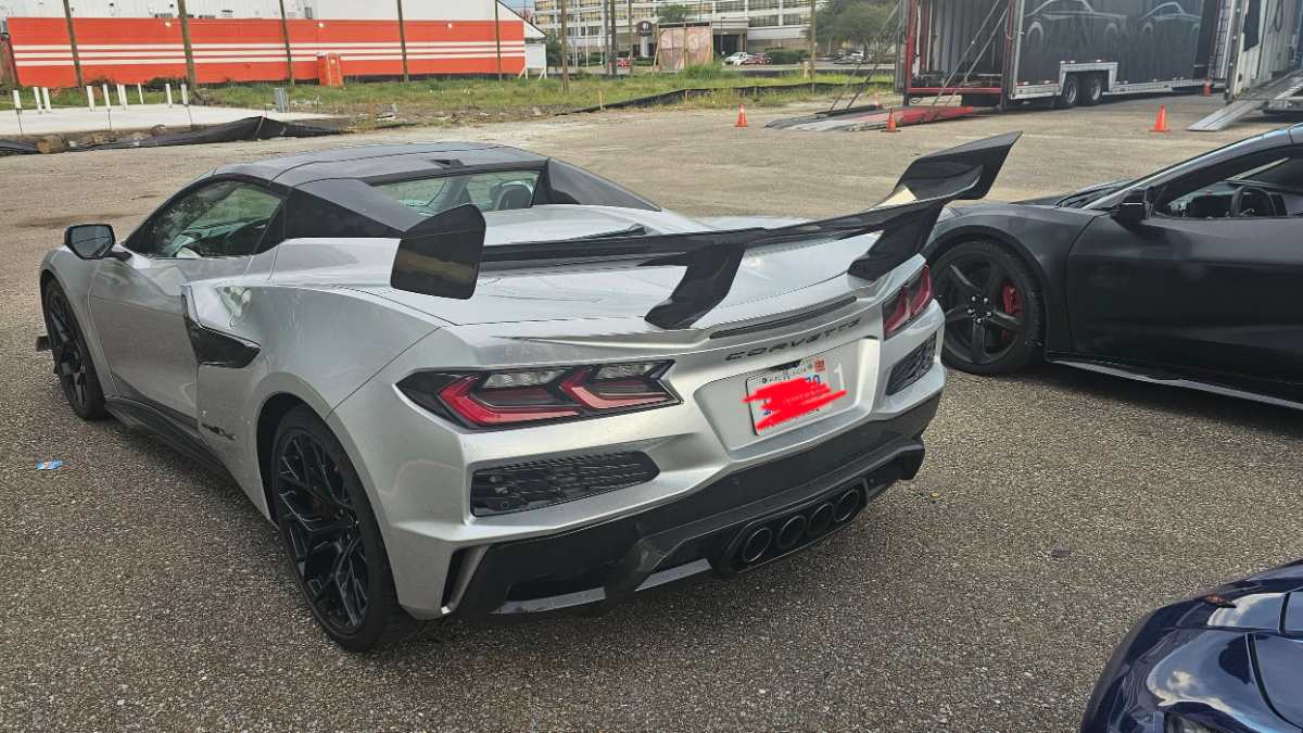 Silver Chevrolet Corvette C8 with black aerodynamic wing and quad exhaust in parking lot