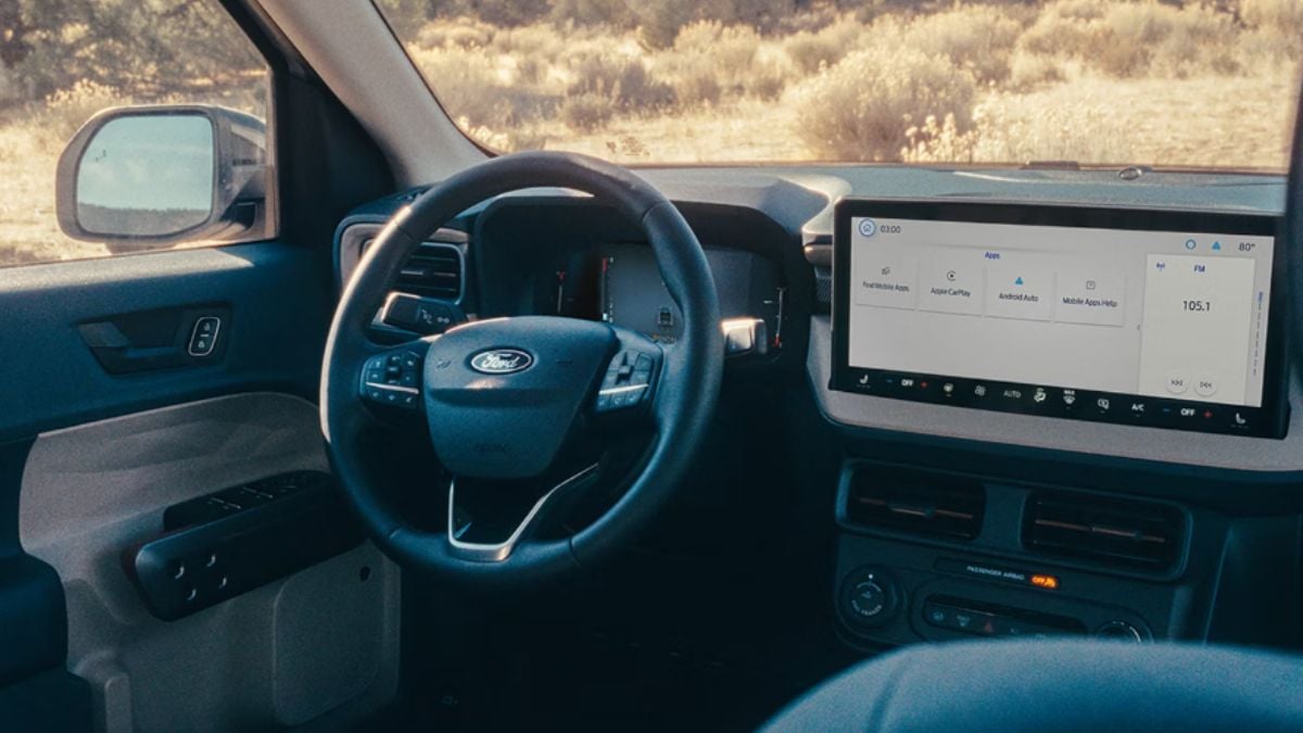 Interior view of a 2026 Ford Maverick vehicle dashboard featuring a large touchscreen infotainment display, leather-wrapped steering wheel, and digital instrument cluster in a dark gray and black color scheme.