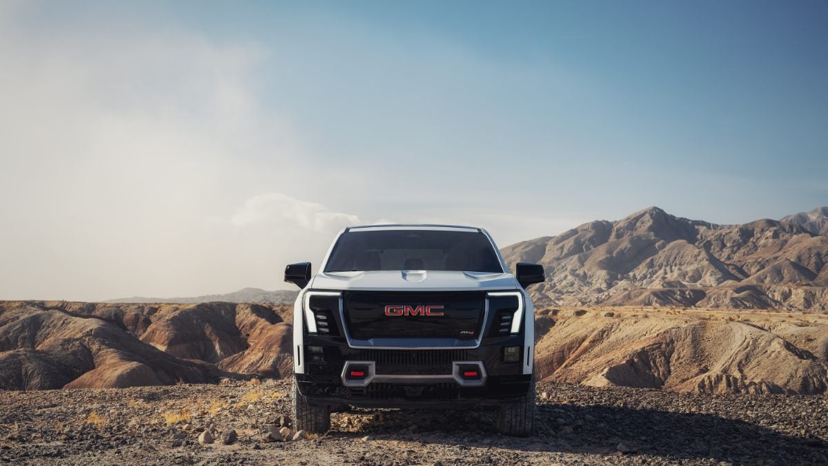 Front view of a GMC truck parked in a rocky desert landscape with mountains.