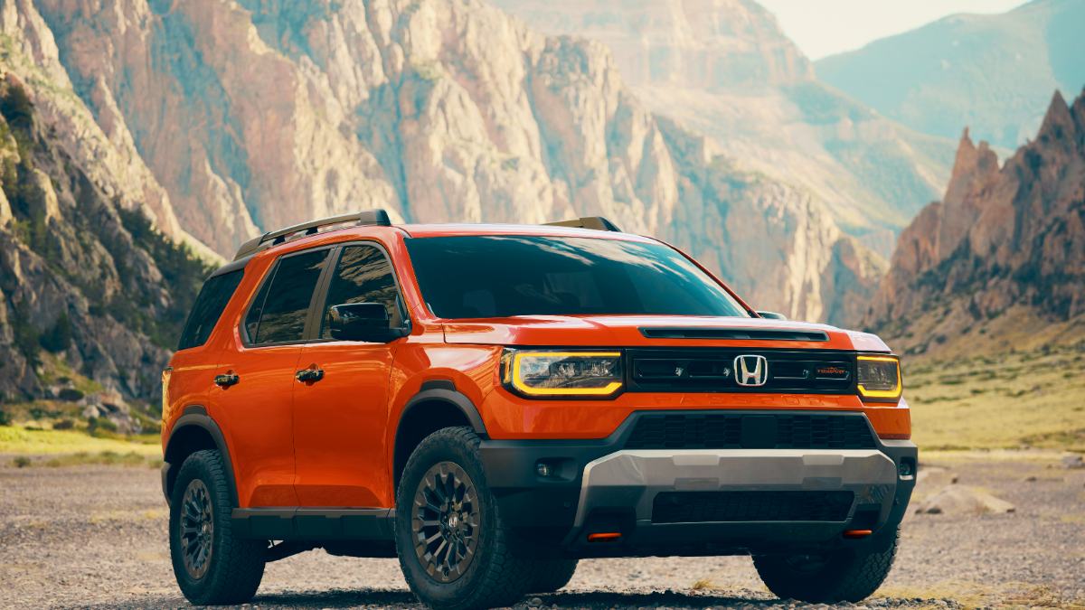 2024 Honda Passport TrailSport in Phoenix Orange, front three-quarter view, showcasing rugged off-road features against dramatic mountain backdrop.