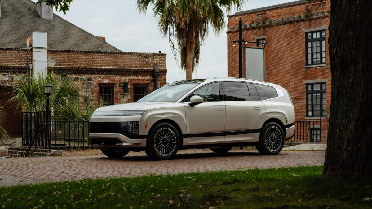 Silver Hyundai Ioniq 9 parked on brick path beside historic red brick buildings and palm tree