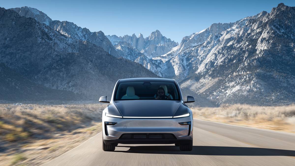 A 2026 Tesla Model Y electric vehicle in the Juniper green color, photographed from the front view while parked with a scenic mountain landscape visible in the background.
