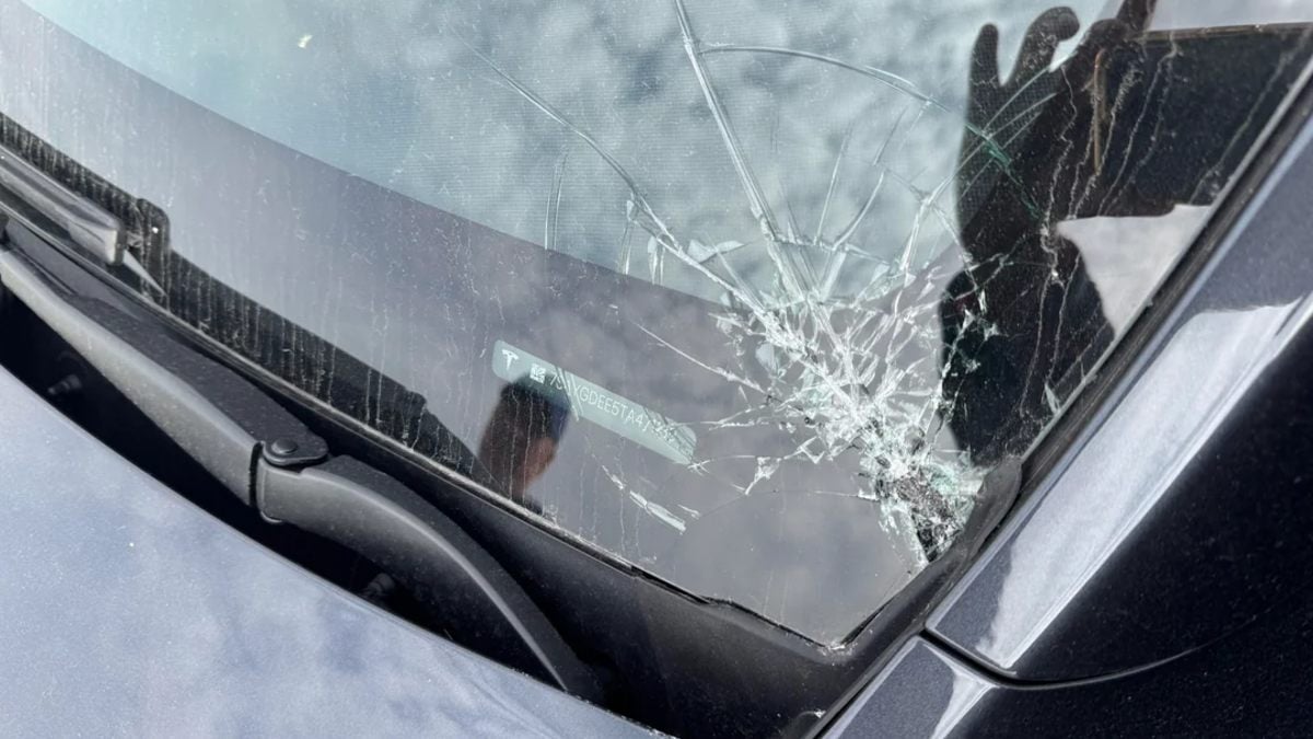Close-up view of a severely cracked windshield with visible spider-web fracture patterns, showing windshield wiper and chrome trim details.