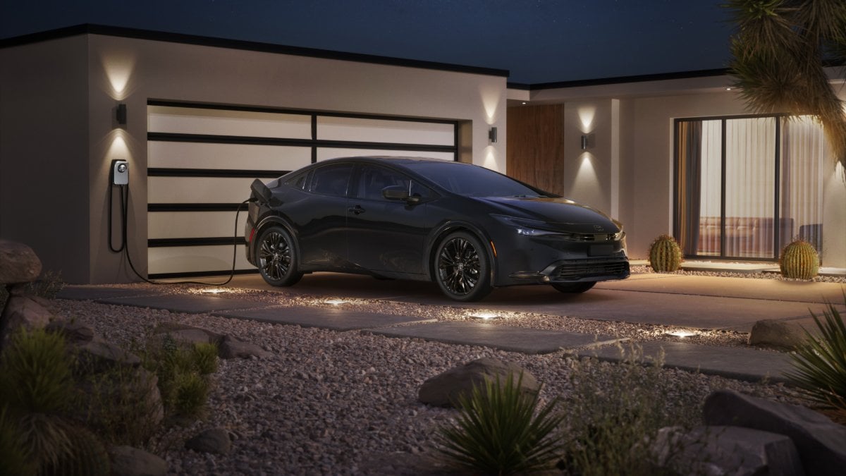 2026 black Toyota Prius Prime charging at a modern home at night under a starry sky.