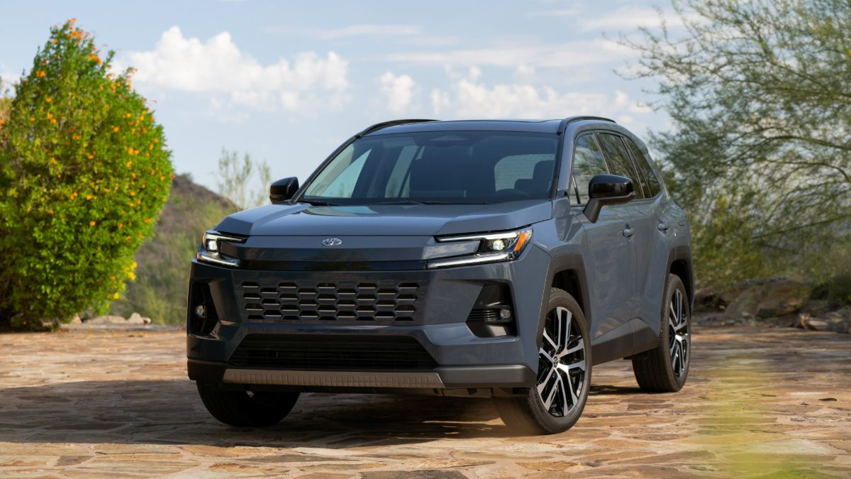 2026 Toyota Toyota Rav4 in metallic gray, front three-quarter view, featuring LED headlights and large black grille, parked on stone surface amid desert landscape.