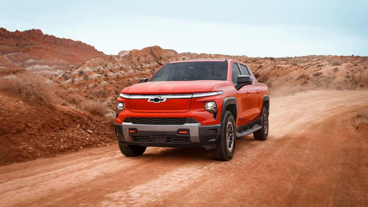 2026 Chevrolet Silverado EV red electric pickup front three-quarter angle in rocky desert landscape showing modern LED lighting and muscular stance.