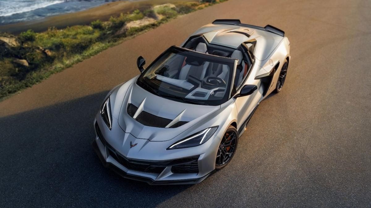 Silver 2026 Chevrolet Corvette ZR1X convertible parked on a coastal road near the ocean, top down, high-performance sports car