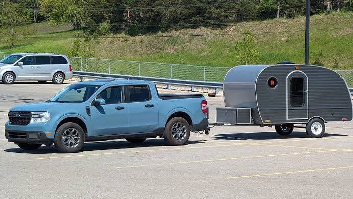 2026 Ford Maverick Hybrid towing a utility trailer and ATV parked in parking lot on a 884-mile trip
