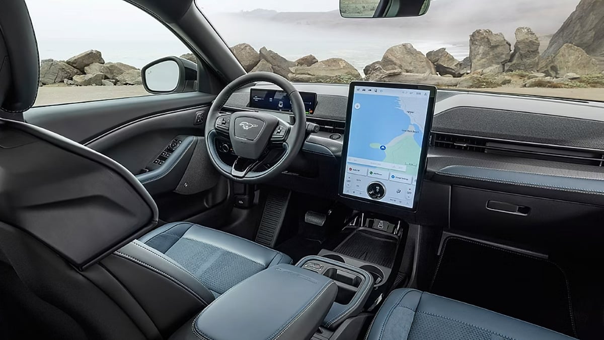 Interior of a Ford Mustang Mach-E featuring its large vertical touchscreen and minimalist dashboard overlooking a coastal landscape.