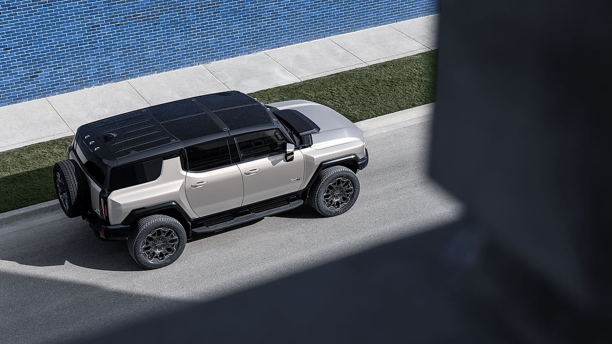 2026 GMC Hummer EV SUV in Granite Drift shown from above on a city street beside a blue brick wall.