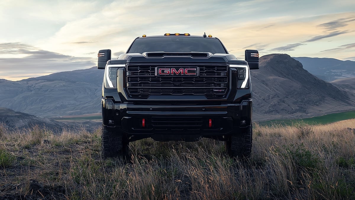 Black 2026 GMC Sierra 2500 AT4 HD shown from the front on a mountain overlook at dusk.
