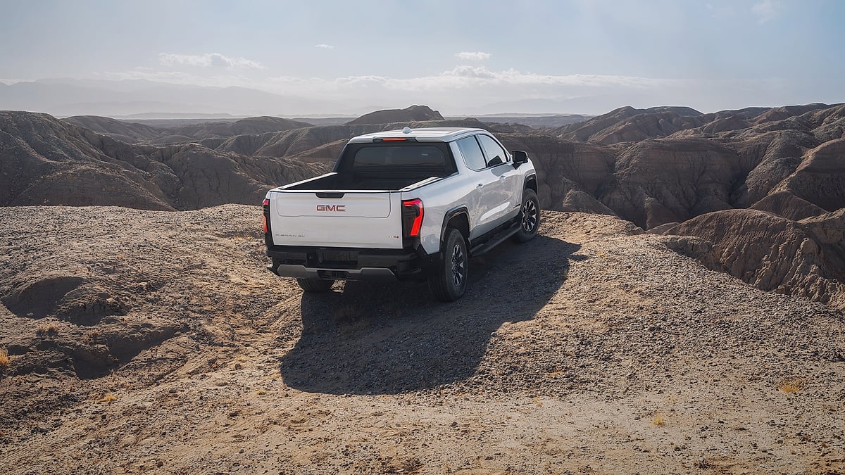 2026 GMC Sierra EV AT4 parked on a desert canyon overlook with rugged hills stretching into the distance.