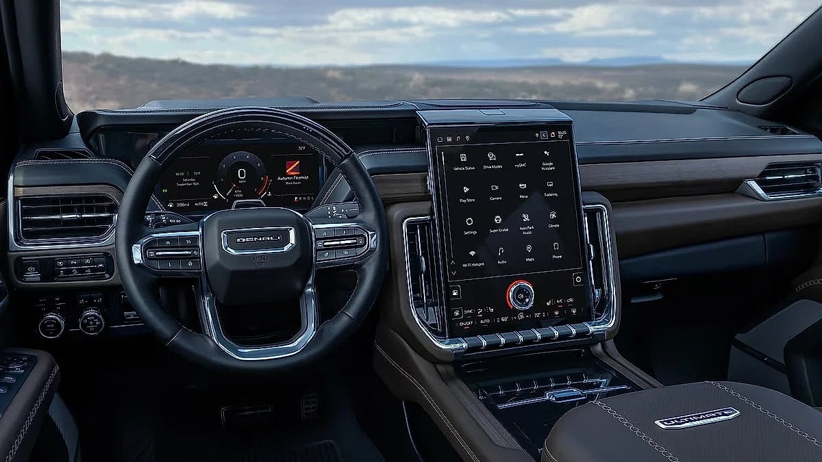 Driver-focused interior of a 2026 GMC Yukon Denali featuring a digital instrument cluster, large vertical infotainment touchscreen, premium materials, and integrated vehicle controls.