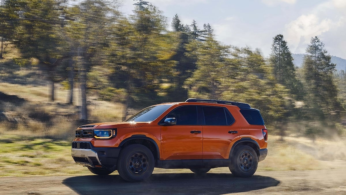 2026 Honda Passport TrailSport in orange driving fast on a dirt road with dust trail in outdoor off-road setting