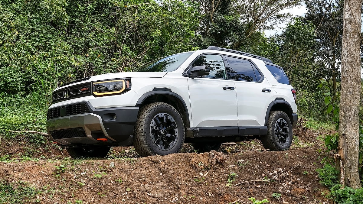 2026 Honda Passport TrailSport Elite off-road SUV driving on rugged dirt trail with all-terrain tires and lifted suspension