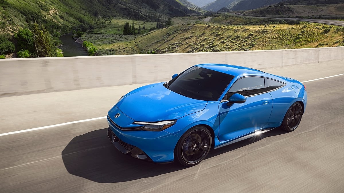 Blue 2026 Honda Prelude driving on a mountain highway, front three-quarter view