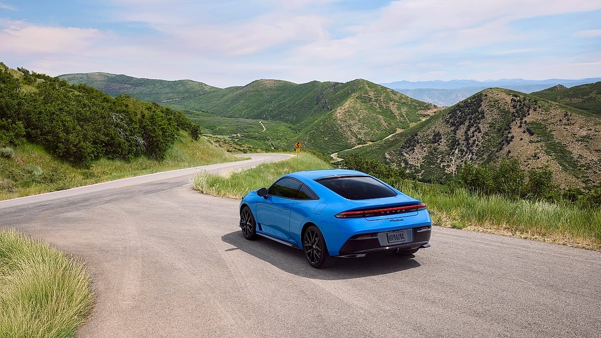 Blue 2026 Honda Prelude on a winding mountain road, rear three-quarter view