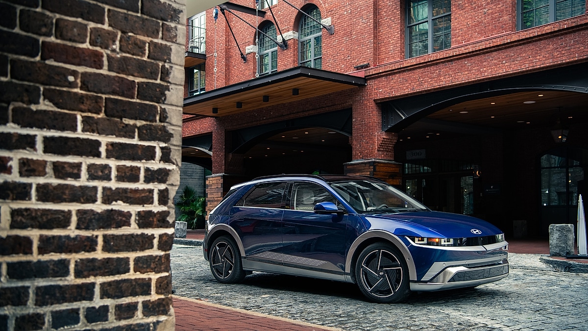 Blue 2026 Hyundai Ioniq 5 parked outside a brick hotel entrance.