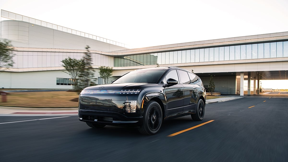 Black 2026 Hyundai Ioniq 9 driving past a modern building in a front three-quarter action shot.