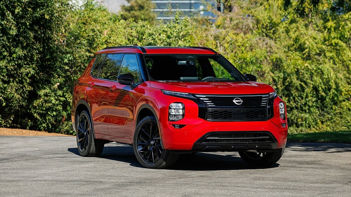 Red 2026 Nissan Rogue Plug-in Hybrid parked in front of greenery.