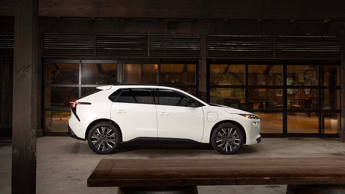 White 2026 Subaru Solterra shown in side profile outside a lodge with large windows.