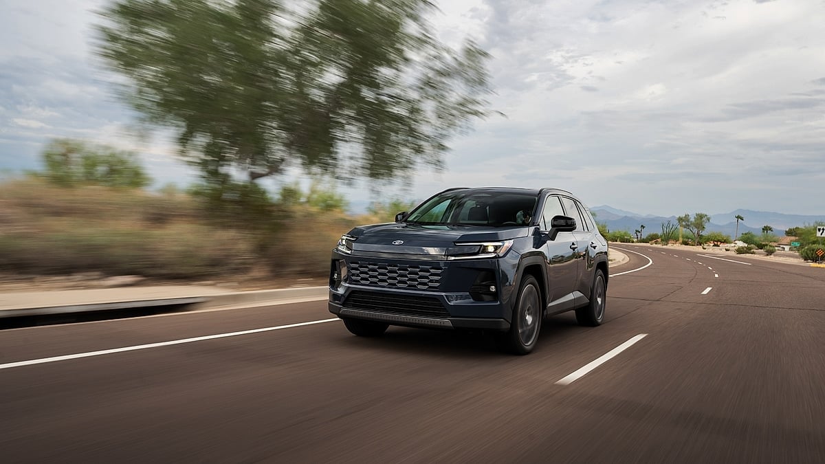 Gray 2026 Toyota RAV4 Hybrid Limited driving on a desert road with motion blur and cloudy sky.