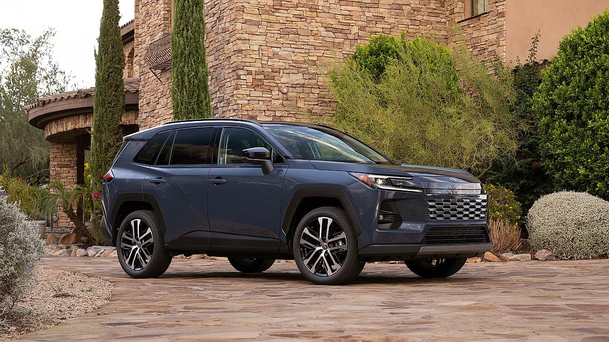 Gray 2026 Toyota RAV4 Hybrid Limited parked in front of a stone house and desert plants.