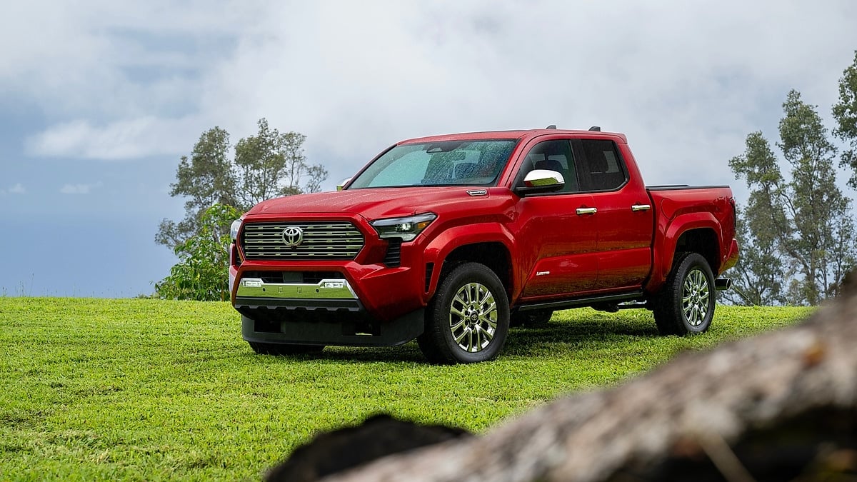 Red 2026 Toyota Tacoma Limited parked on green grass in a front three-quarter view.