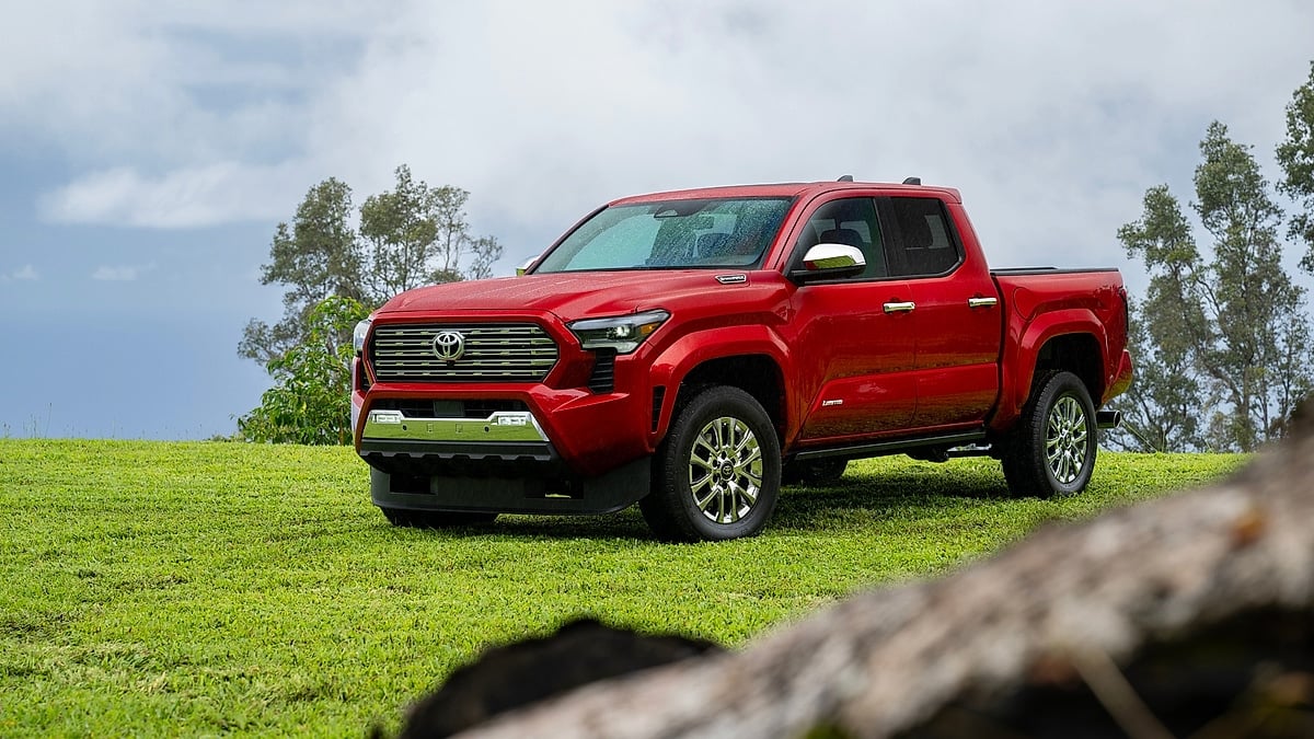 Red 2026 Toyota Tacoma Limited parked on a green hillside with cloudy skies behind it.
