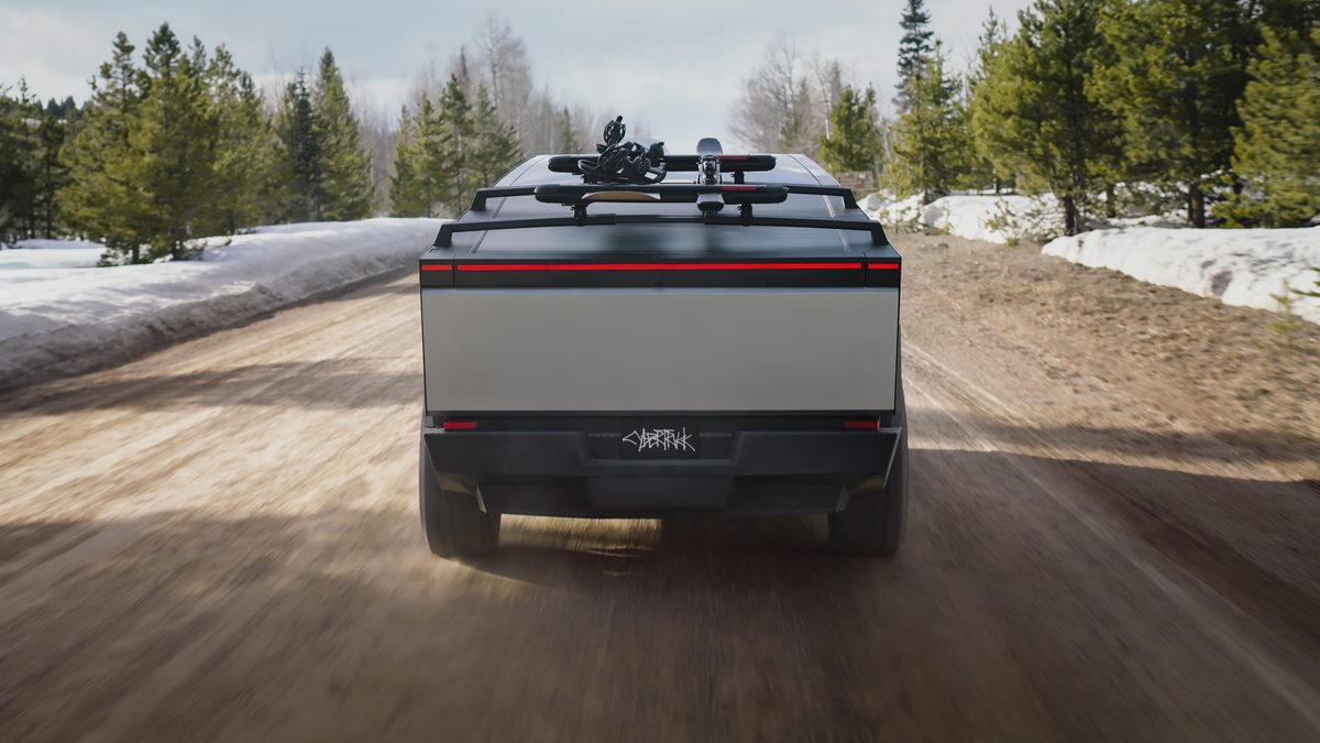 Rear view of Tesla Cybertruck driving on a winter gravel road with snowbanks