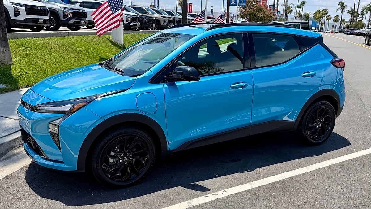 Blue 2027 Chevrolet Bolt RS parked near a dealership in a side-profile view with black wheels.