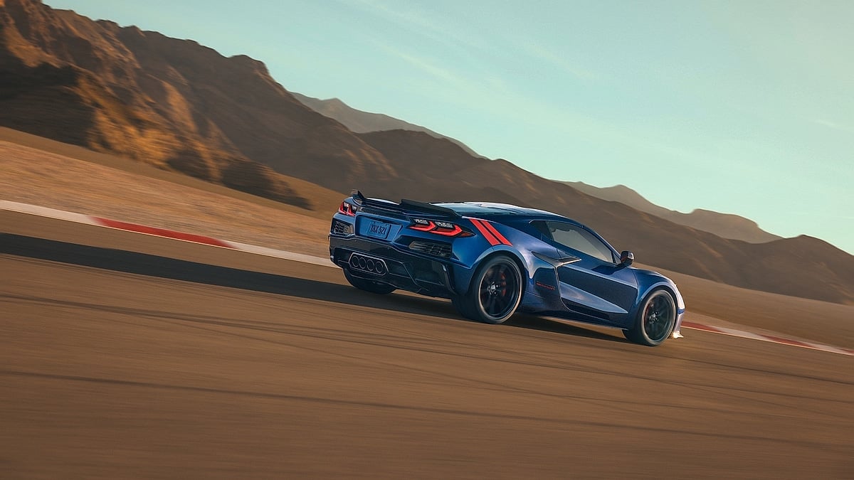 Rear three-quarter view of a blue 2027 Chevrolet Corvette GS driving on a racetrack.